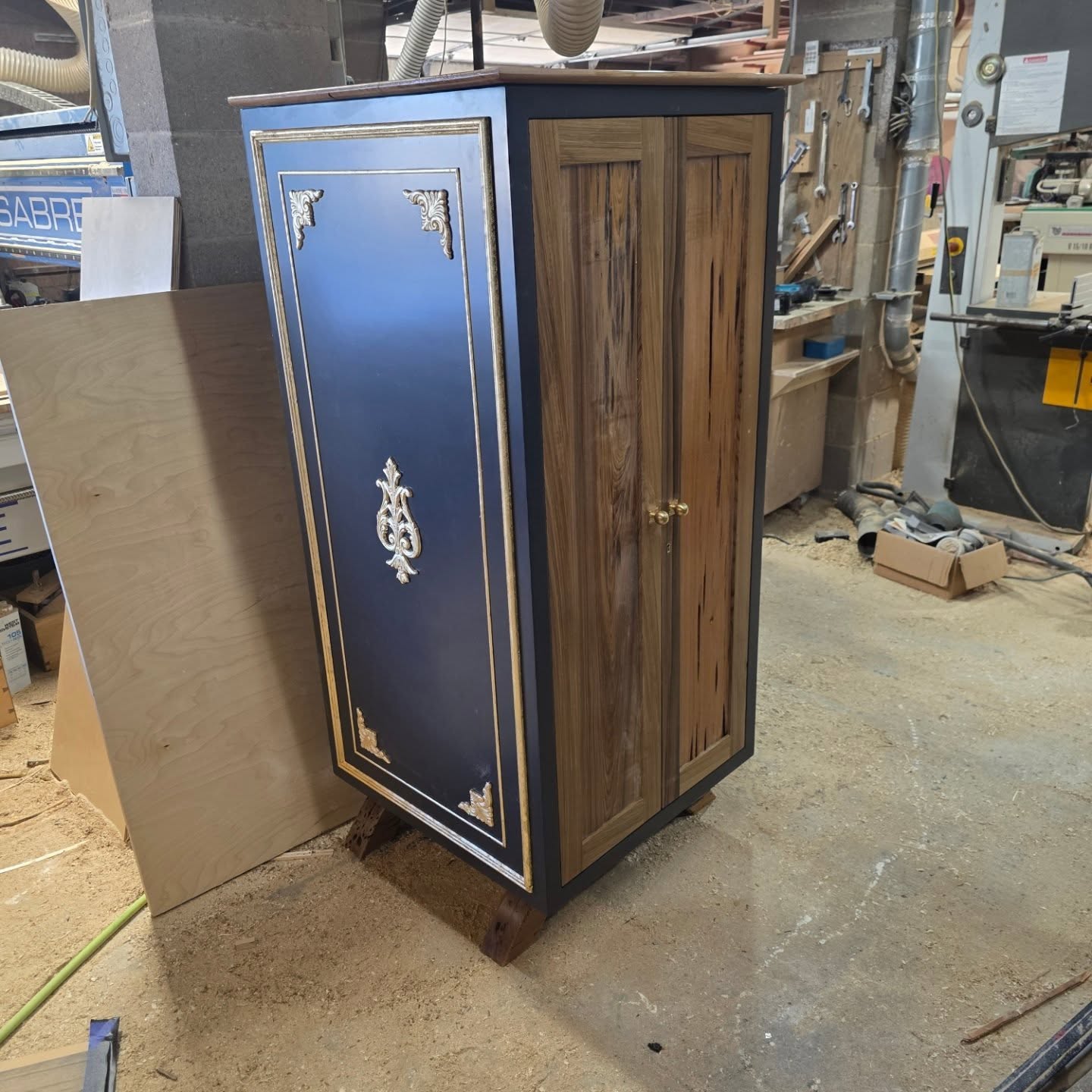 Black bar cabinet with gold-leaf ornament standing in the shop