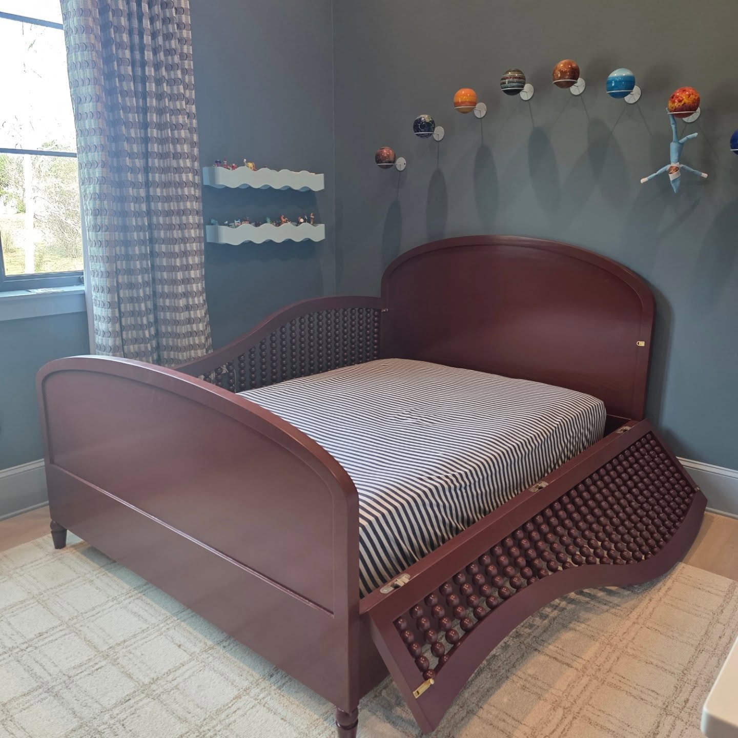 Curved footboard of a child's bed, finished in deep red