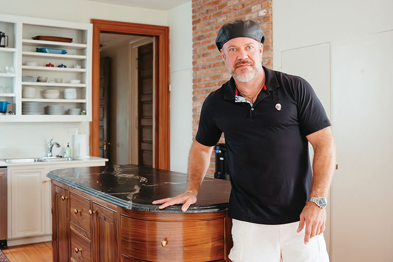 Andrew Nixon standing beside a curved walnut kitchen island
